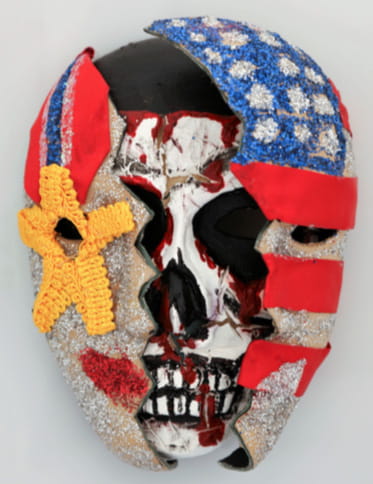 A mask that appears to be split with a skull on the inside that also depicts a medal and an American flag on the outside.