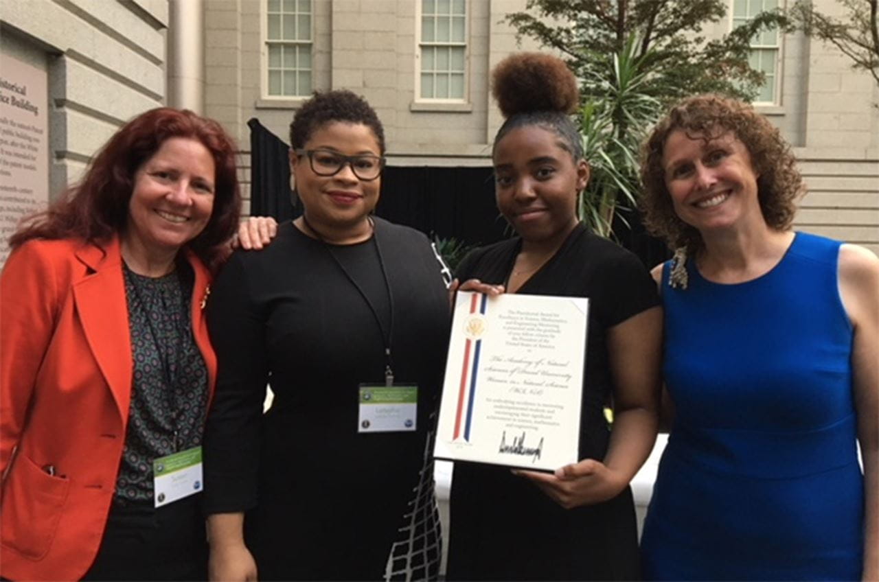 Four women involved with the WINS program gathered around their award certificate.