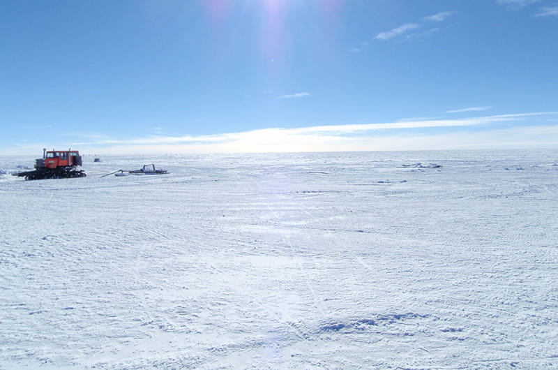 The East Antarctica landscape with a heavy tractor in the background