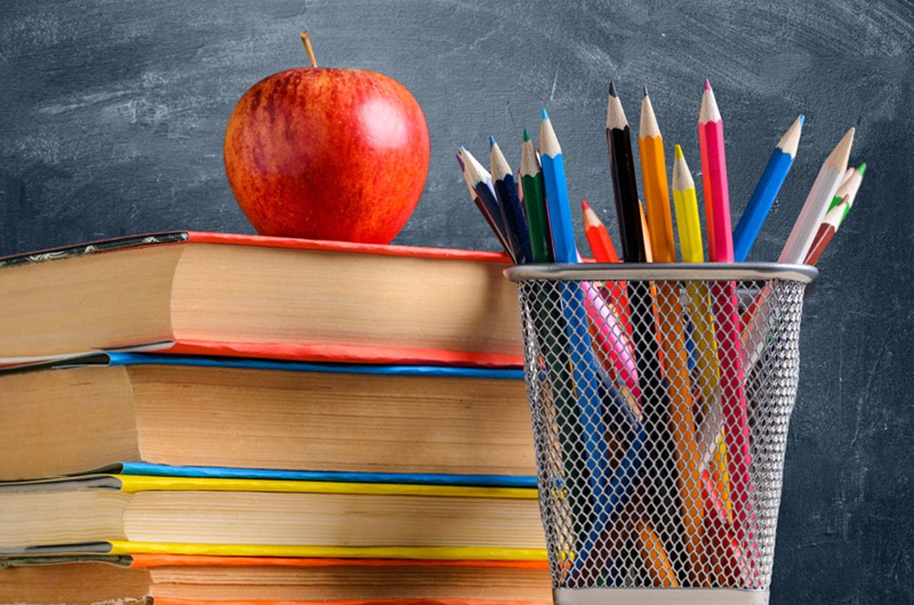 Back to School. Accessories, books and fresh apple against chalkboard