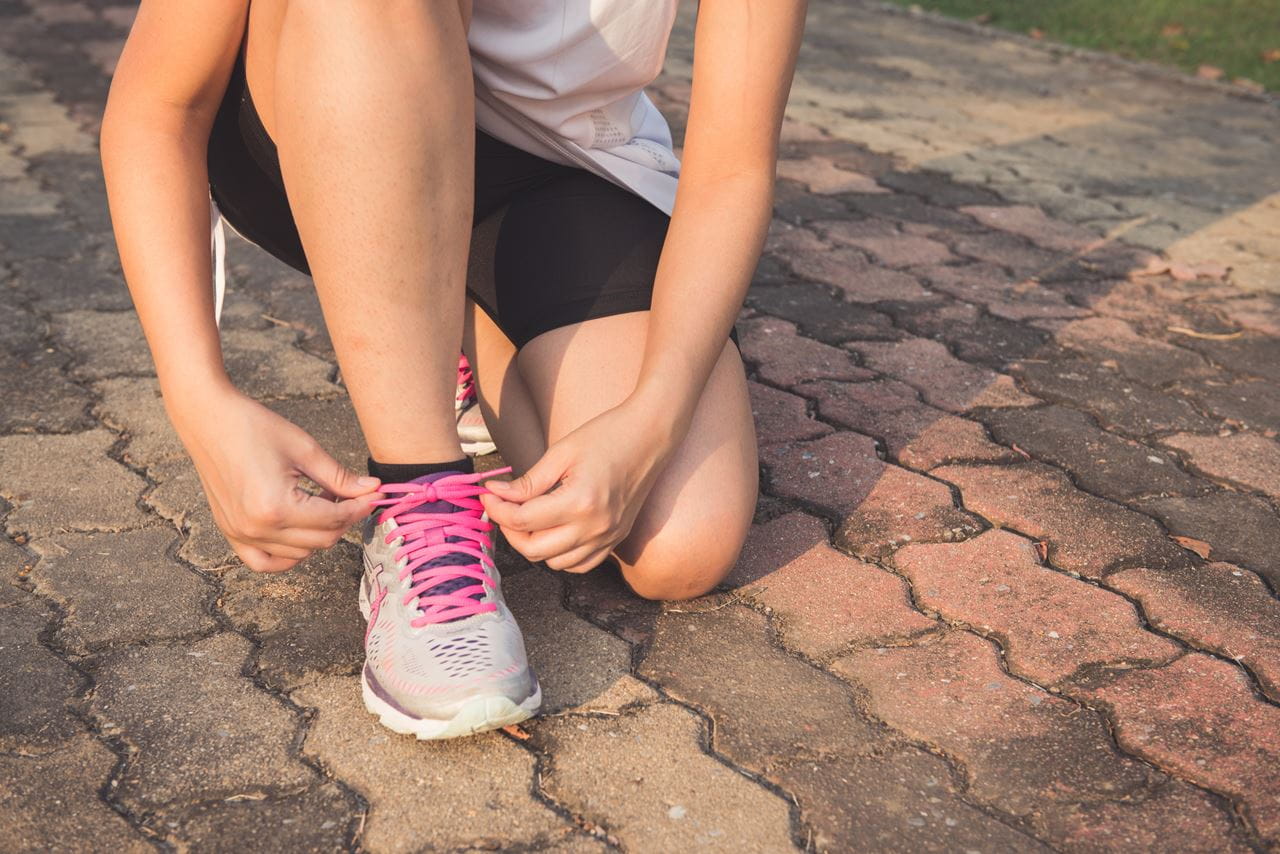 Woman tying shoes in exercise clothes