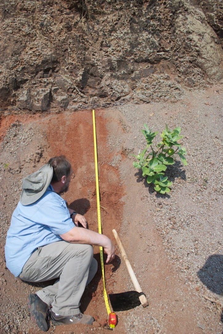 Prof. Paul Renne inspects profile of a red bole within the Ambenali Formation near the town of Mahabaleshwar. Image credit, Loÿc Vanderkluysen.