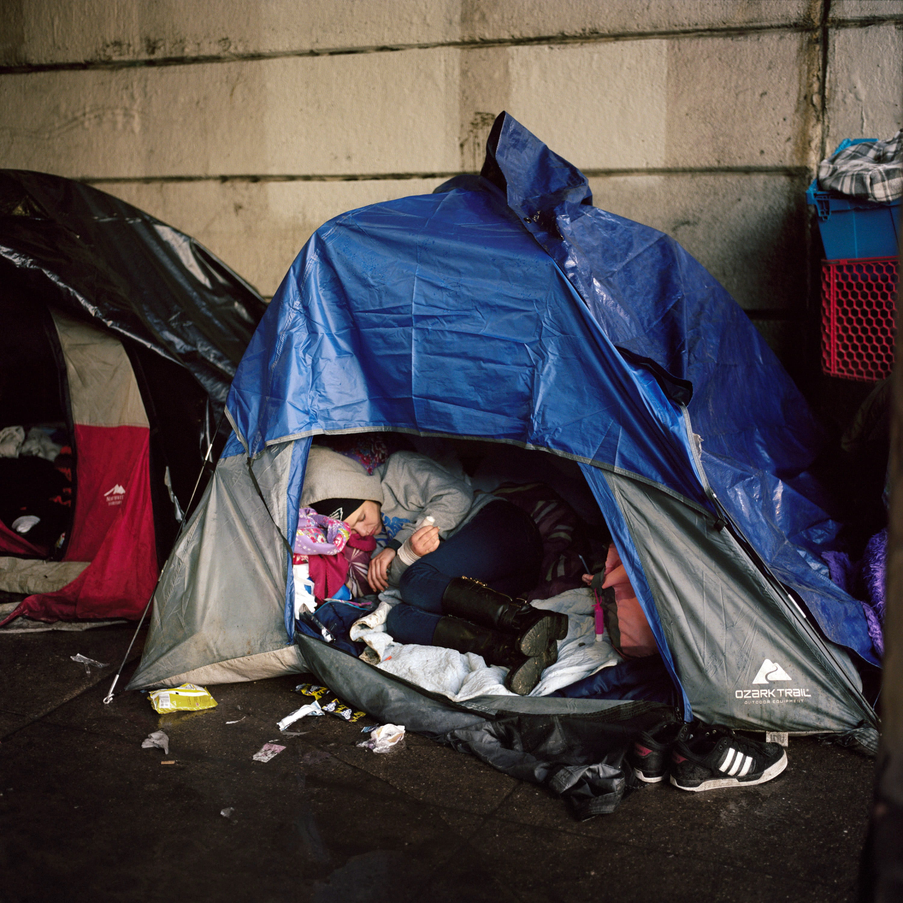 A young woman sleeps in a tent beneath the Kensington Avenue underpass, 2018. After hundreds of homeless drug users were evicted from the abandoned tracks in Kensington during the summer of 2017, many users relocated underneath the Kensington Avenue underpass as well as three other tunnels in the neighborhood.