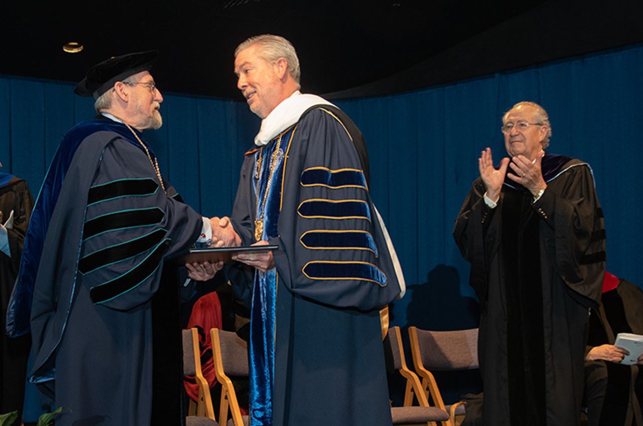 Gratz College President Paul Finkelman, PhD, shakes hands with Drexel University President John Fry as Gratz College Board of Governors member Leon L. Levy looks on.