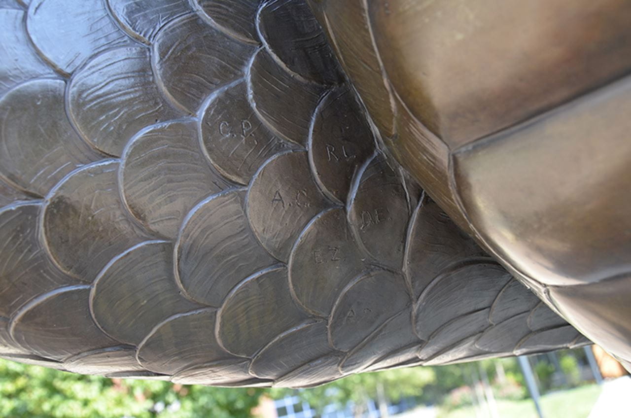 The initials on the raised arm of the "Mario the Magnificent" statue. "CP" stands for Constantine Papadakis. "AC" is for Anthony Caneris. "EZ" is for Eric Zillmer. 