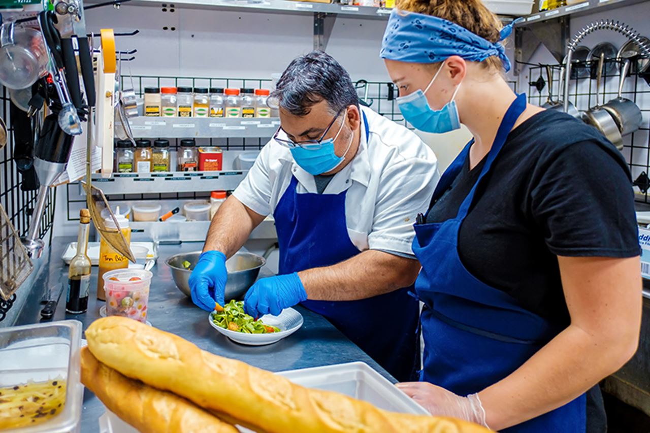 Executive chef Brian Lofink ’03 and Drexel University fifth-year and co-op student Anna Wilson plate a panzanella salad in the kitchen of terrain’s garden café in Glen Mills, Pennsylvania.