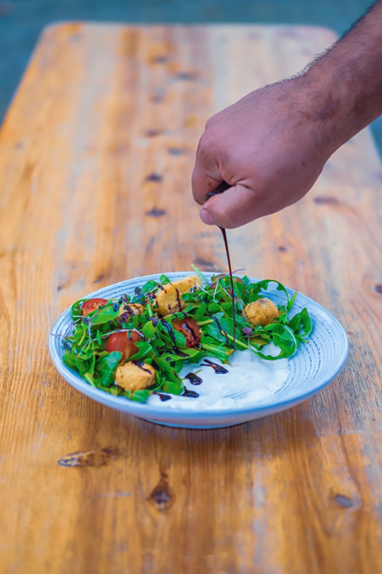 Panzanella salad heavy on tomatoes with cherry tomatoes on a bed of crisp arugula, croutons made of green tomatoes coated in breadcrumbs and deep fried, and an oven-dried tomato-basil vinaigrette.