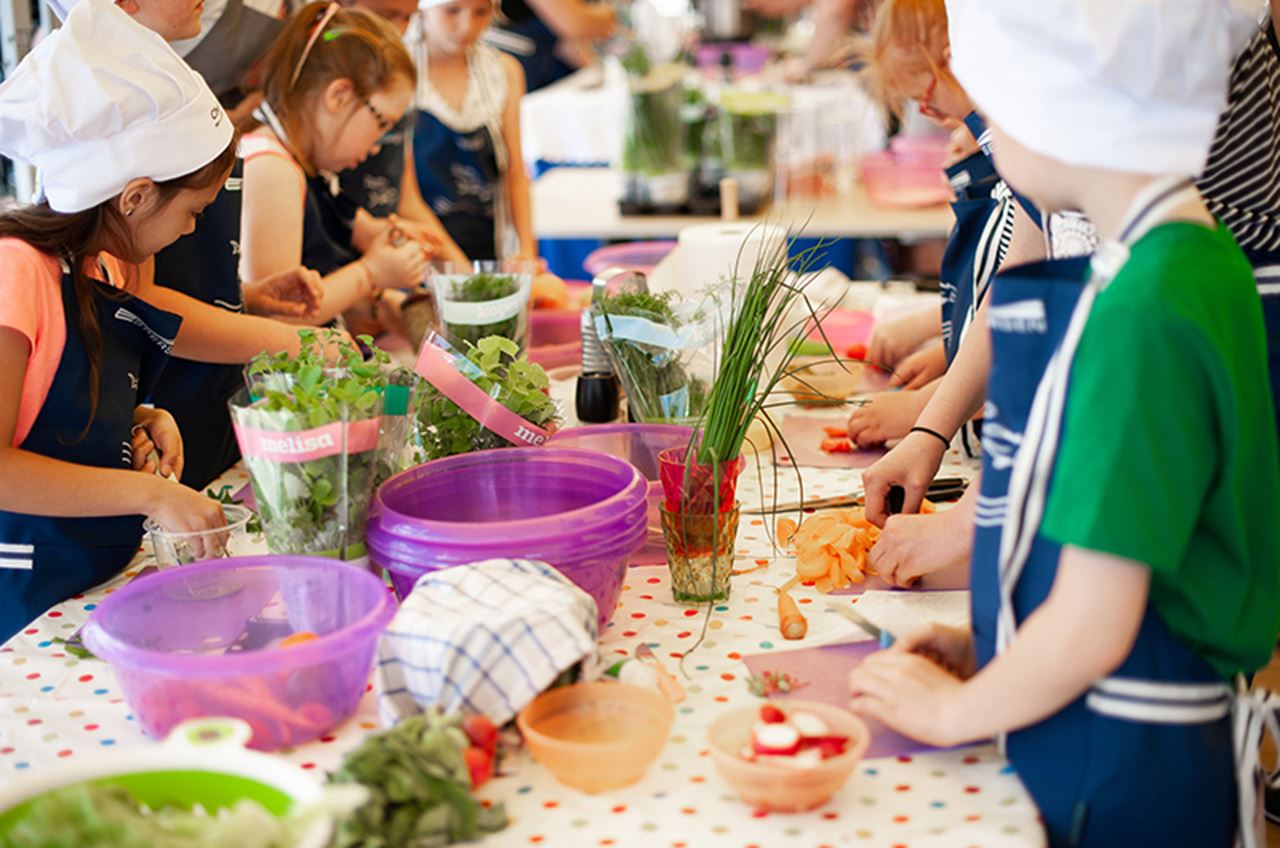Several young kids prepping vegetables