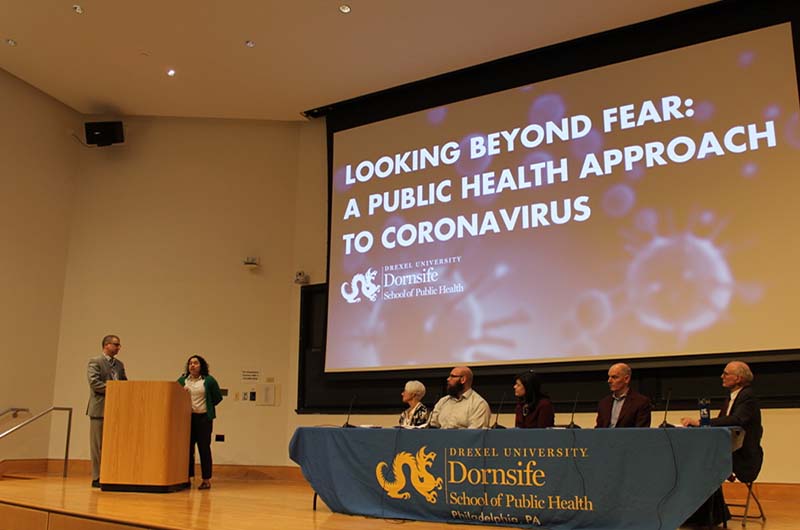 At the Dornsife event, Michael Yudell, PhD, is pictured standing at the podium as Janet Cruz, MD, spoke. Seated from left to right were panelists Annette Molyneux, PhD; Michael LeVasseur, PhD; Esther Chernak, PhD; Joseph Amon, PhD; and James Buehler, MD.