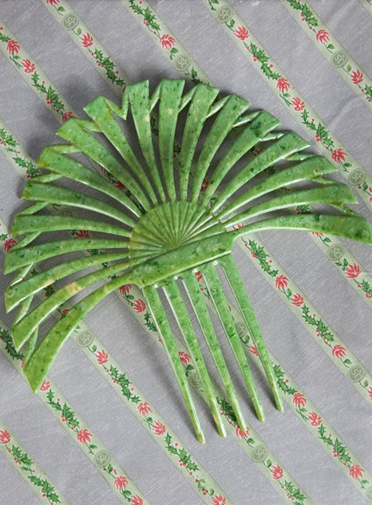 One of the combs purchased by Naomi Ford, on top of the original holly wrapping paper. Photo credit: Robert and Penny Fox Historic Costume Collection. Credit: Gift of Mrs. Anne Wright.