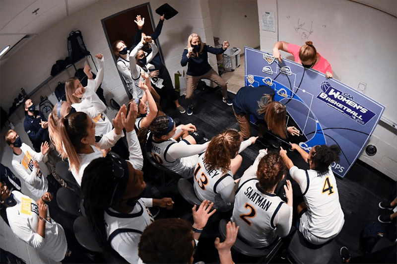 Coach Mallon and the team celebrating in the Drexel locker room after the JMU win. Drexel’s athletic trainer Kerri DiPietro is validating the win by placing the Dragon logo in the CAA finals!  