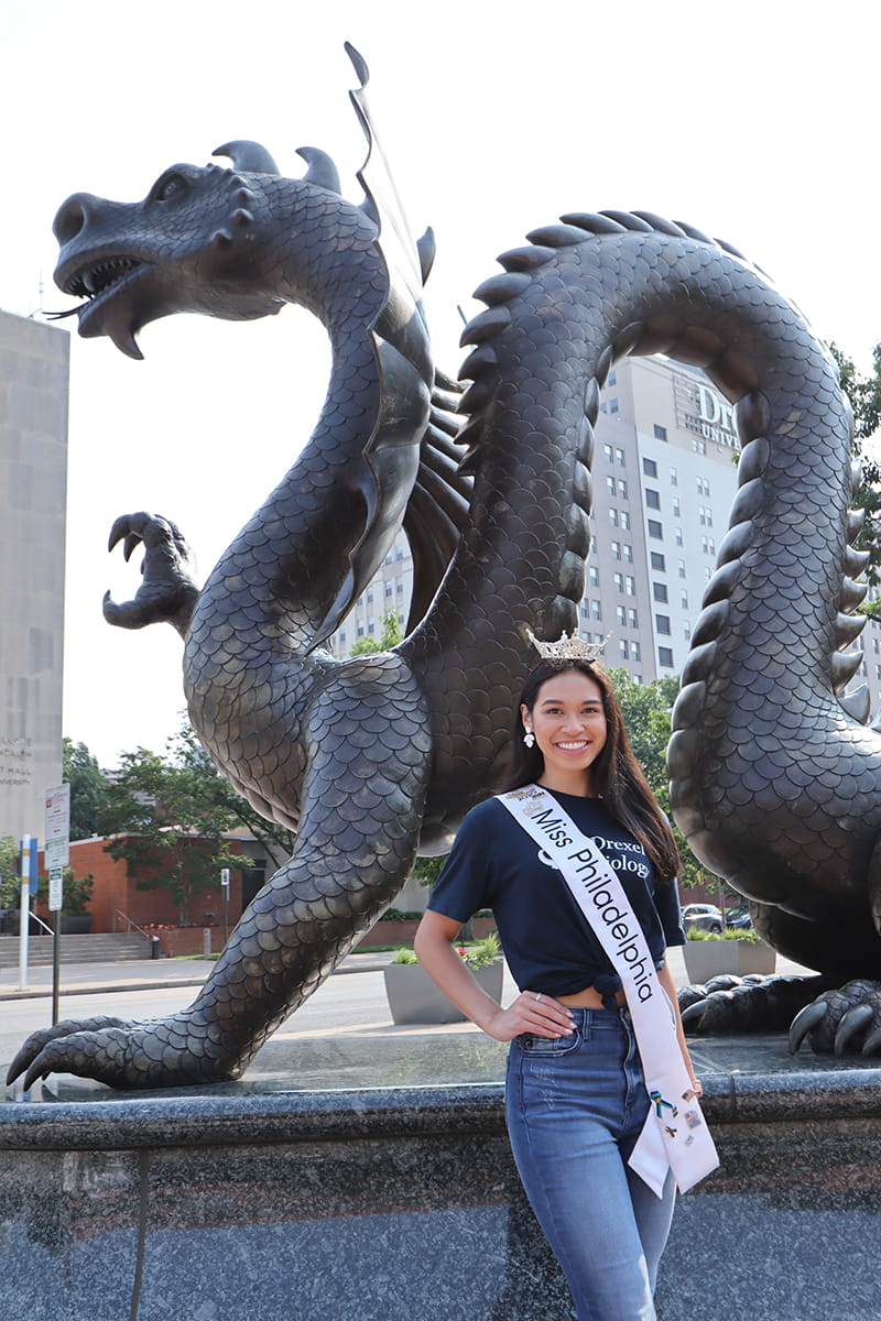 Elaine Ficarra, a rising third-year biology major and Pennoni Honors College student who earned the title of Miss Philadelphia, poses in front of the Dragon statue. 