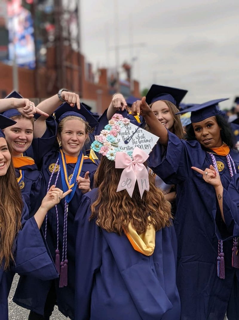 Students show off a classmate's decorated cap with a ribbon.