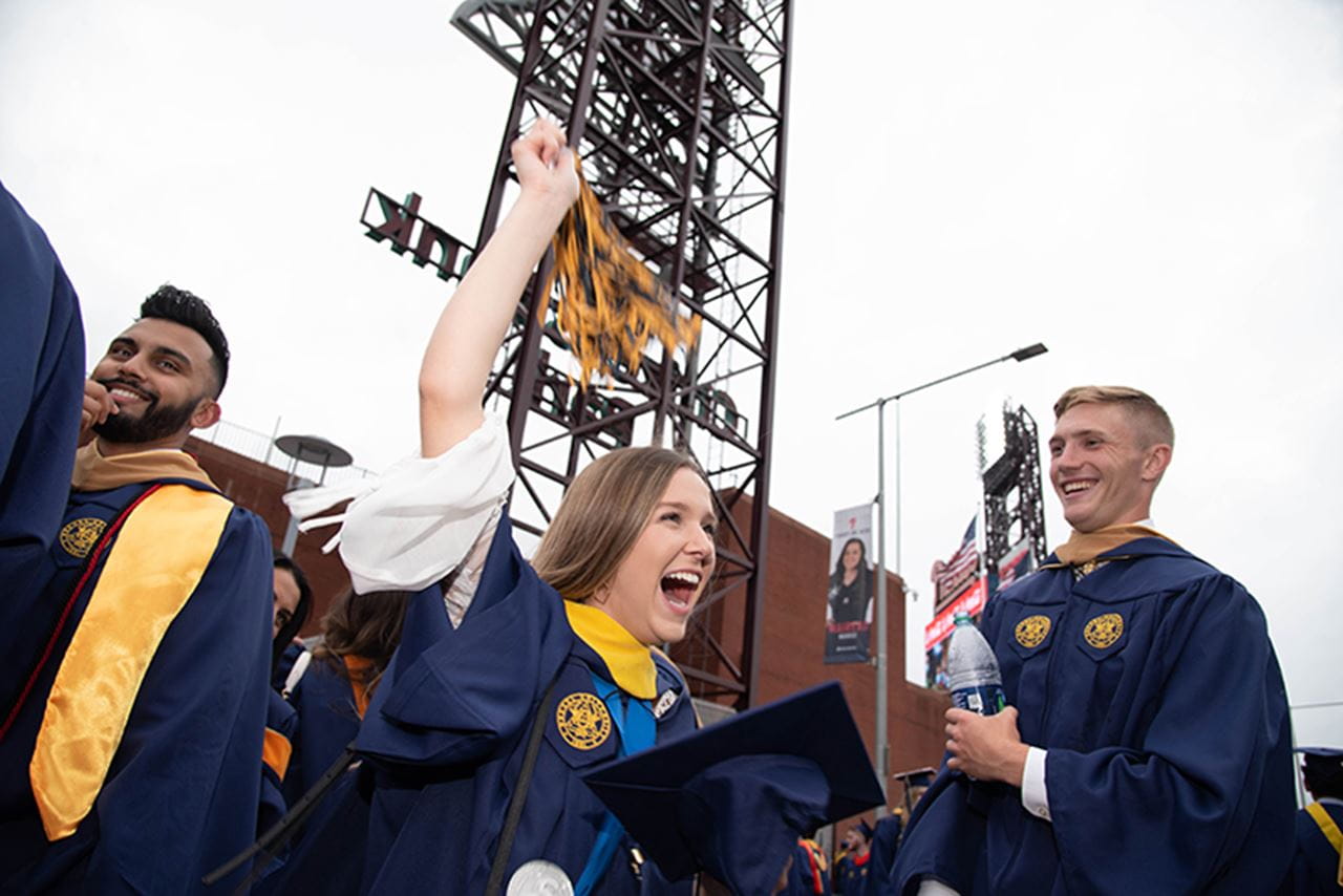 Student cheers and raises arm at ballpark.