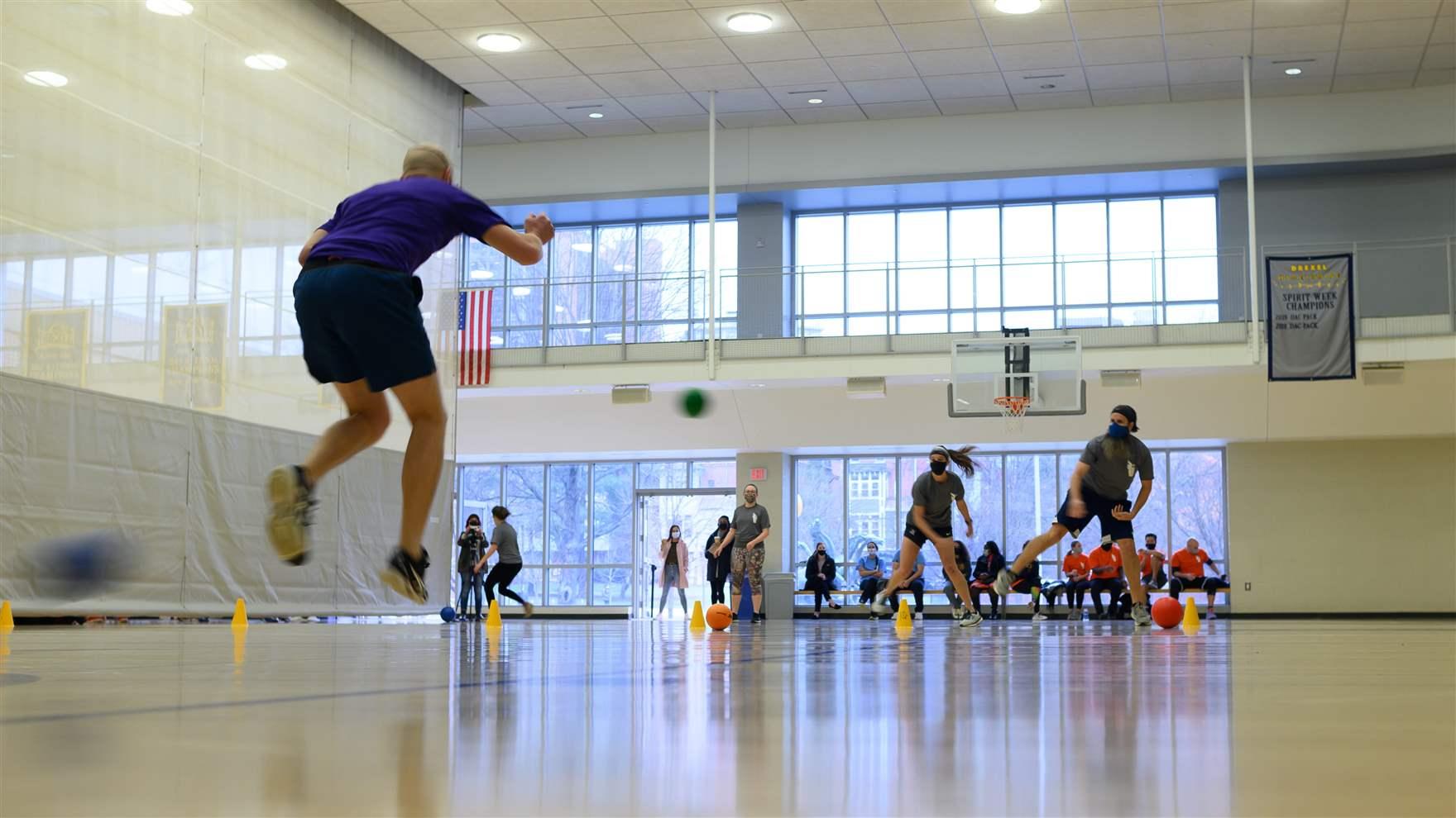 A man jumps to avoid being hit while playing dodgeball. 