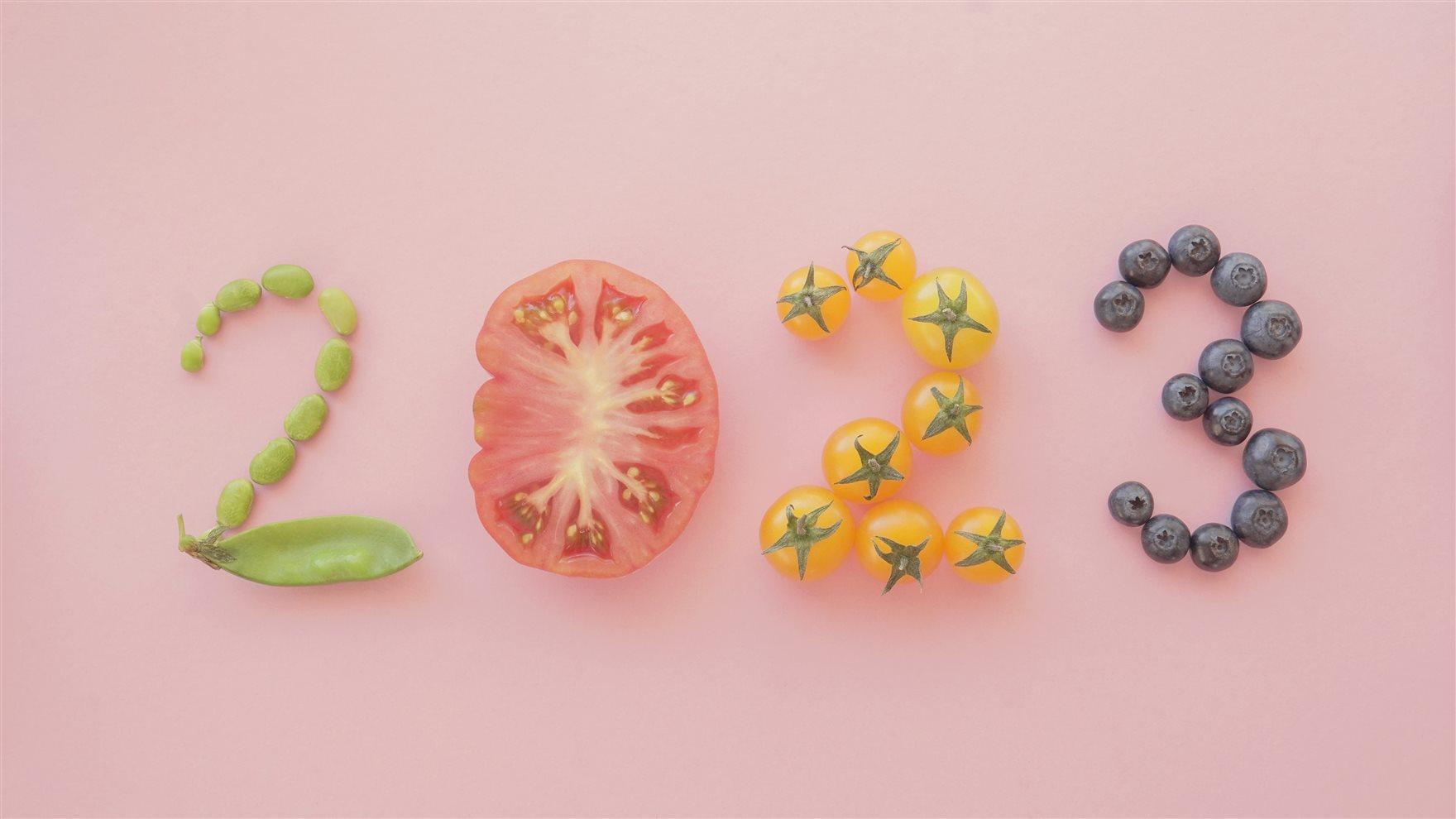 2023 written out using peas, a tomato slice, cherry tomatoes and blueberries.