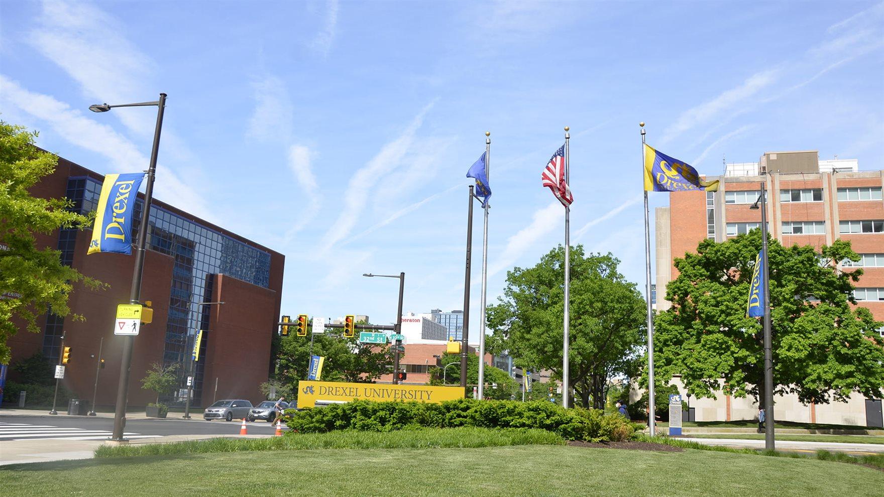 Drexel flags and signage in a grassy area on 32nd and Market streets.