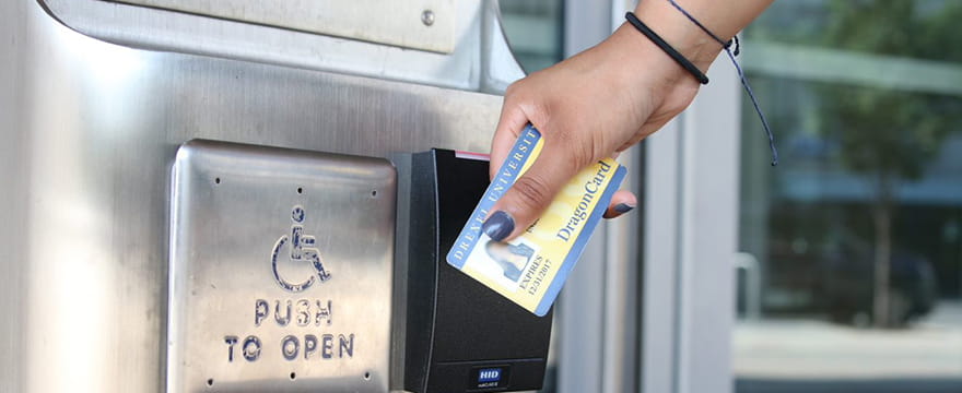 Image of a hand holding a DragonCard to a scanner outside of a Drexel building.