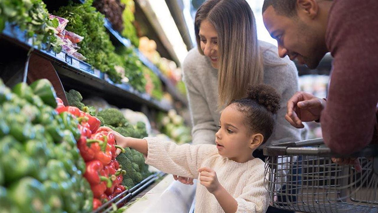 A family of three shopping for produce