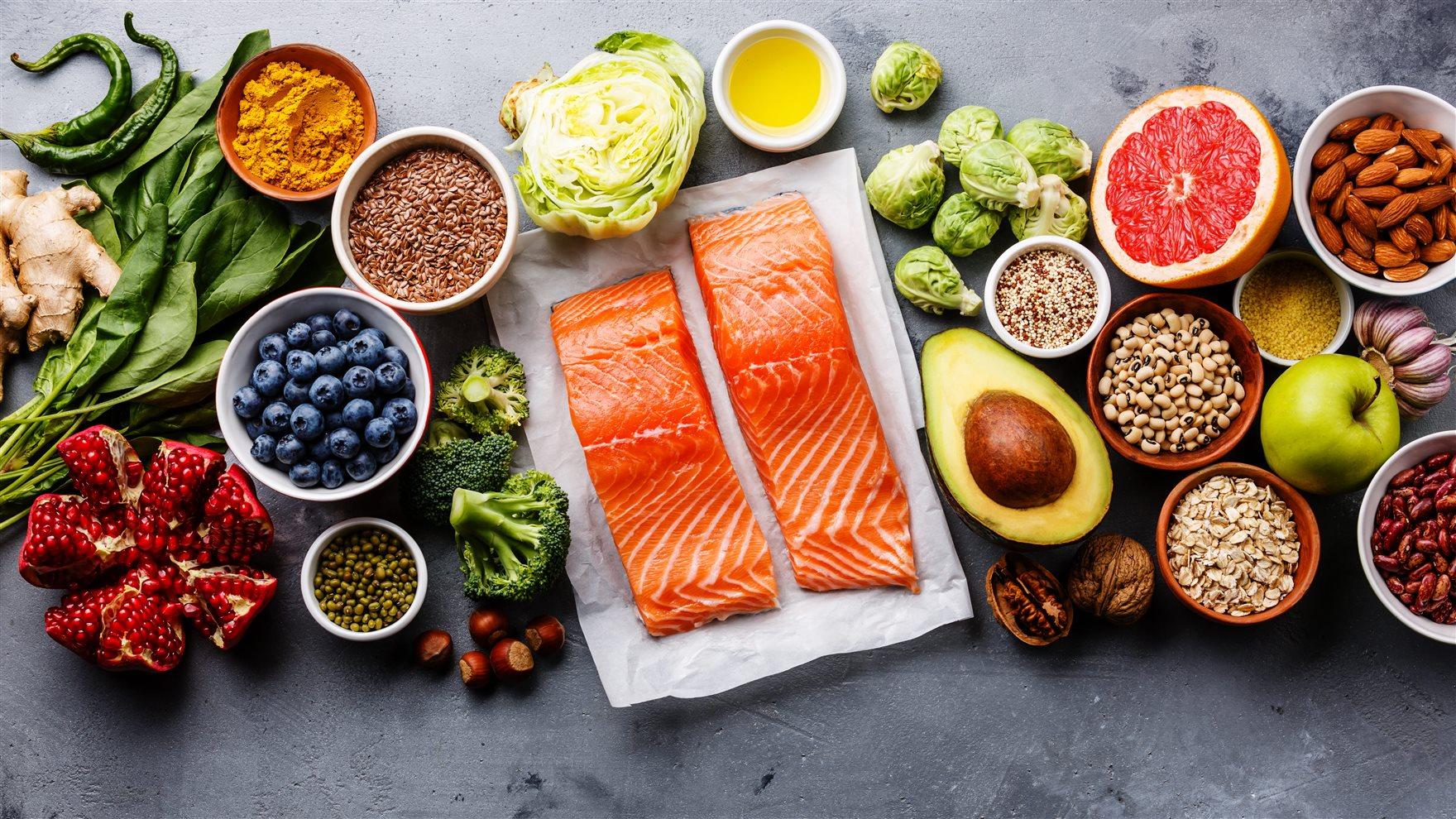 A row of healthy foods including berries, avocados and salmon.