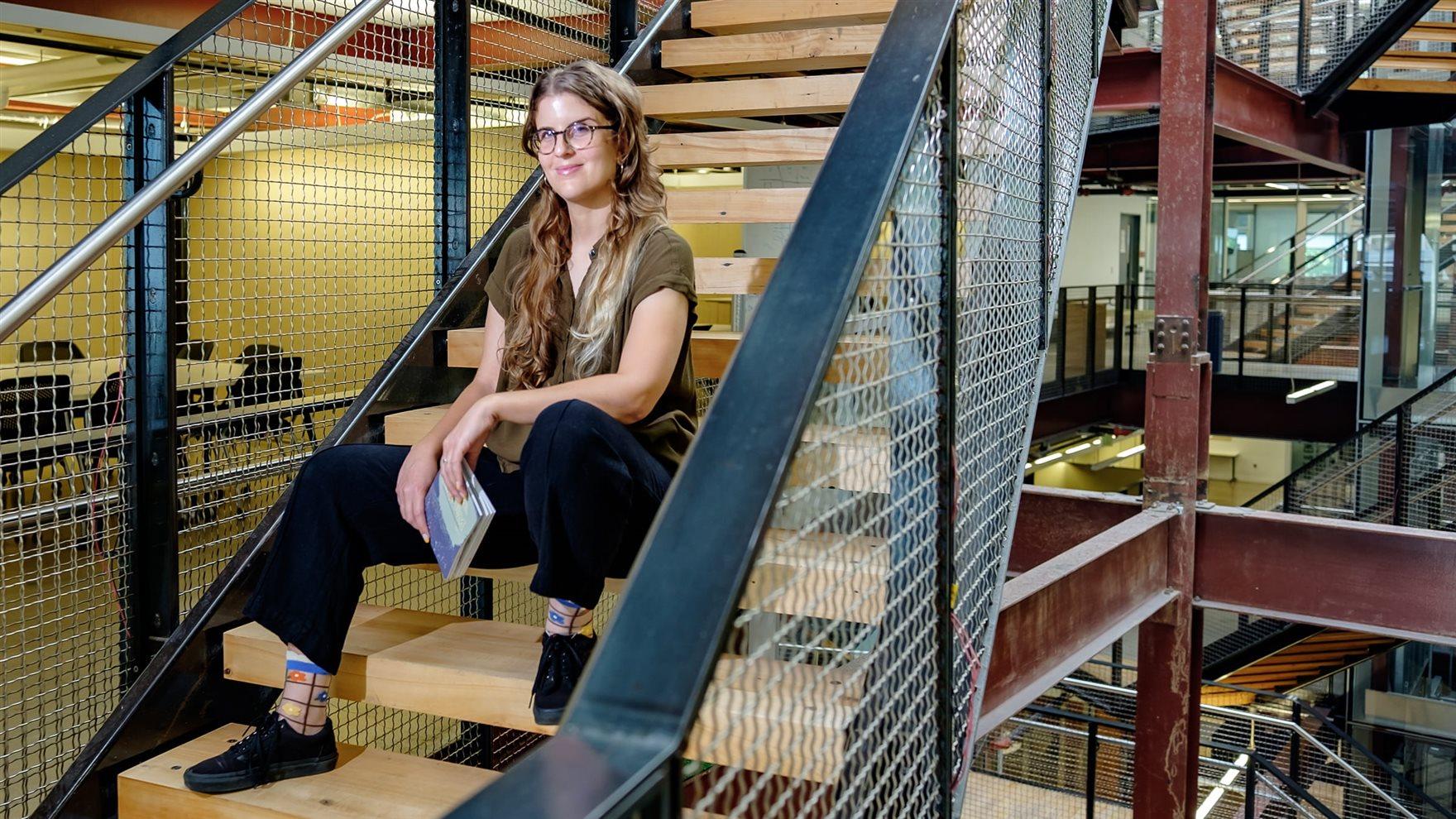 Monika Julien sits on a staircase holding an issue of "Double Platinum."