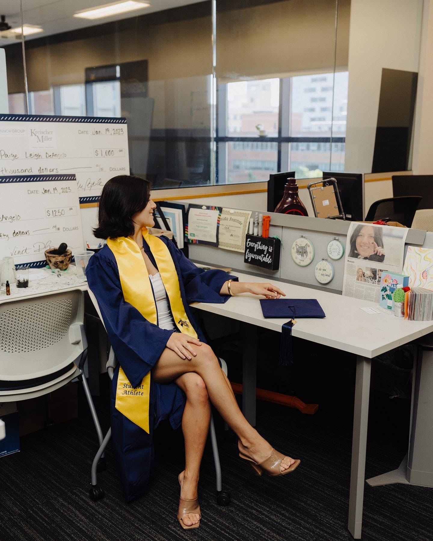 Paige Deangelo in graduation gown at co-op desk