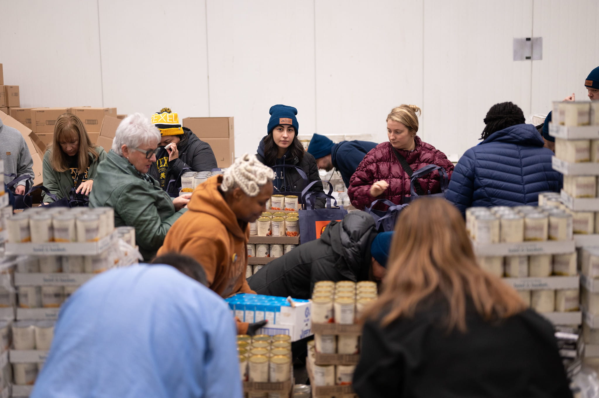 Drexel alumni surrounded by non-perishable items they packed during a Dec. 9 event.