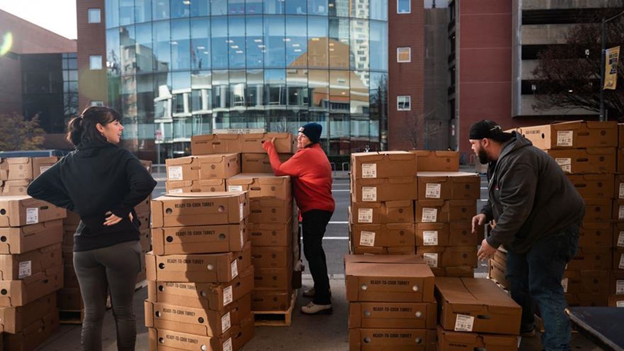 Three people move a tower of boxes.