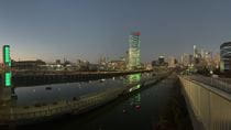 A panoramic view of the Philadelphia skyline at sunset showing buildings and objects lit up in green, from the green towers of South Street Bridge to Center City skyscrapers.