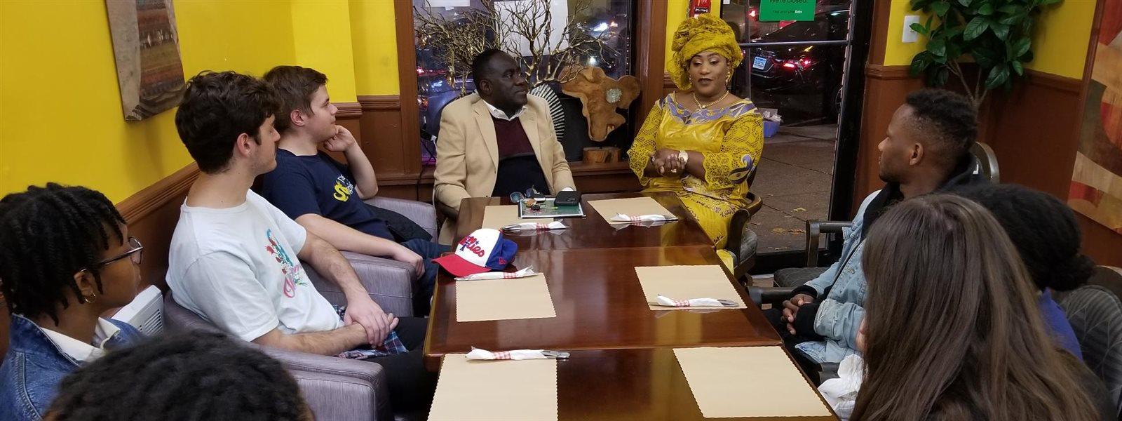 Students discussing African small businesses in West Philly with AFRICOM President and Chief Operating Officer, Eric Edi, PhD, and Youma Bah, a Senegalese entrepreneur, at Bah&#39;s Kilimandjaro restaurant at 45th Street and Baltimore Avenue. Photo credit: Parfait Kouacou, PhD.