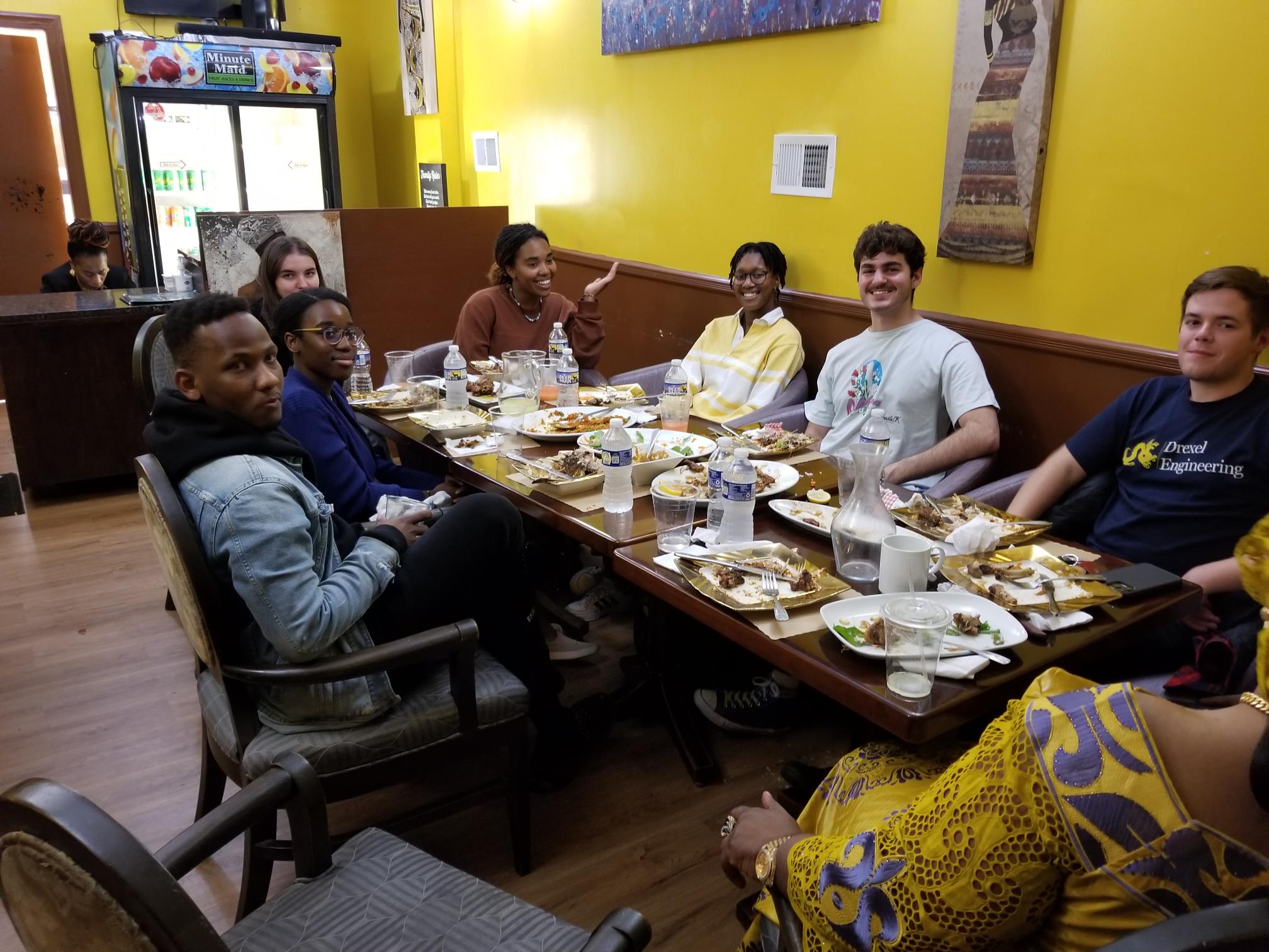 Students seated at a table after sampling African food at Kilimandjaro. 