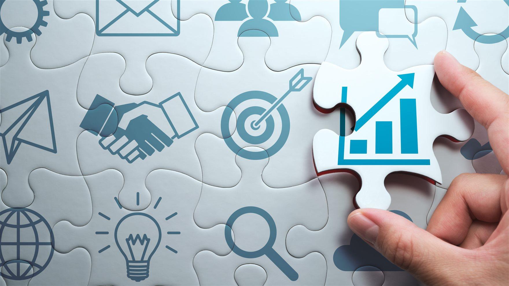 Image of a hand putting a puzle piece showing a map of growth in a puzzle with other iconography  related to career success, like an email and a lightbulb and a handshake and a magnifying glass.