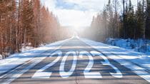 The word 2023 is written on a highway in the middle of an empty asphalt road at dawn and a beautiful blue sky. New year 2023 concept.