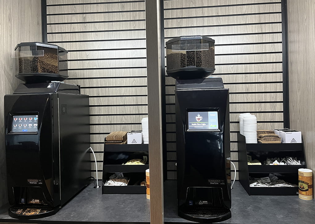 Two coffee machines side by side with various coffee accoutrements.