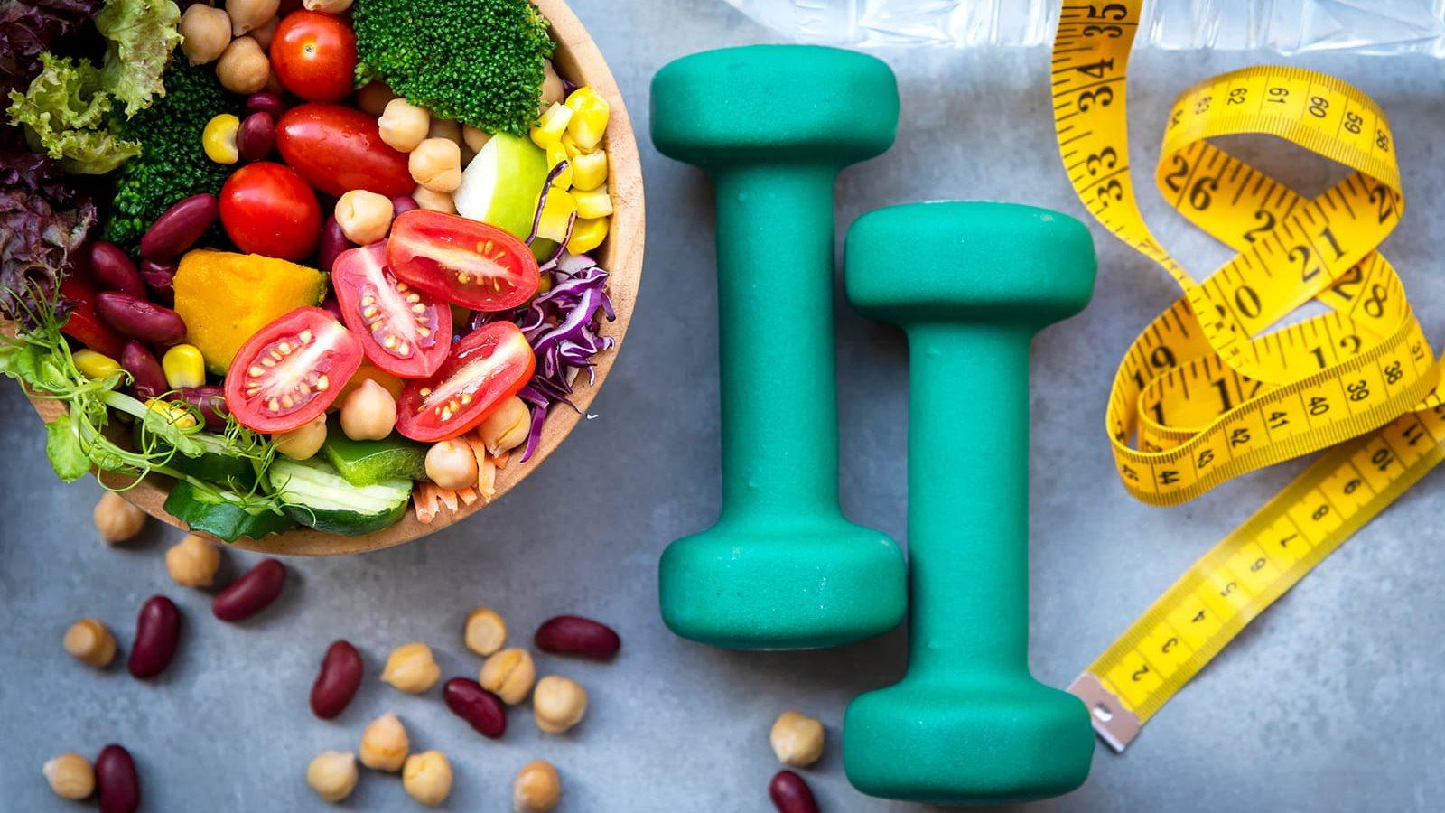 bowl of salad, handheld weights and tape measure