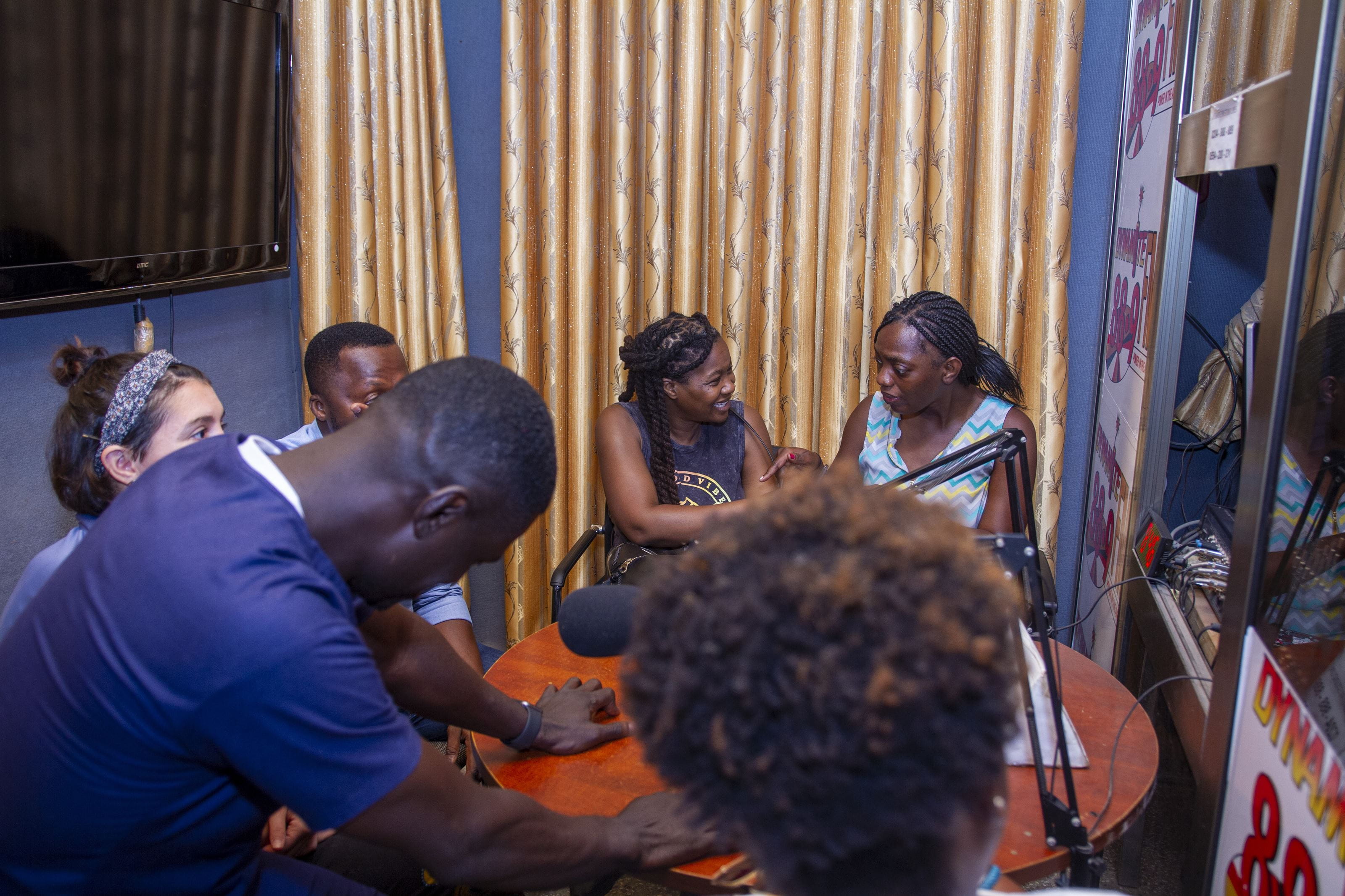 Six people seated in a room with their heads down.