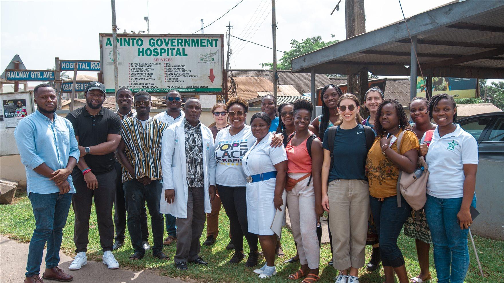 A group of people stand outside in front of a sign reading "Apinto Government Hospital." Photo courtesy Ebony White.