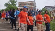 A group of people in orange shirts lead a group down some stairs.