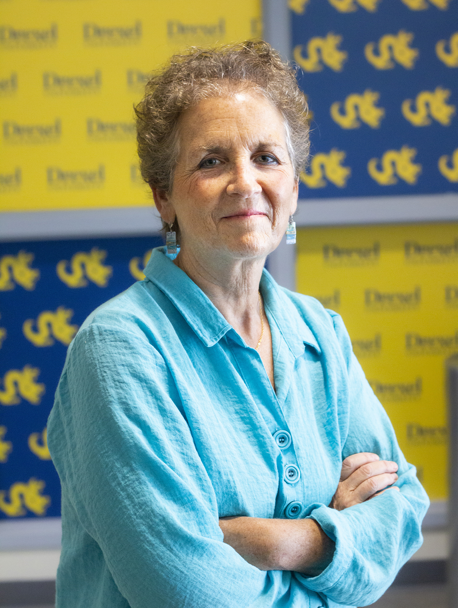 Marla Gold stands with her arms crossed in front of Drexel logos.