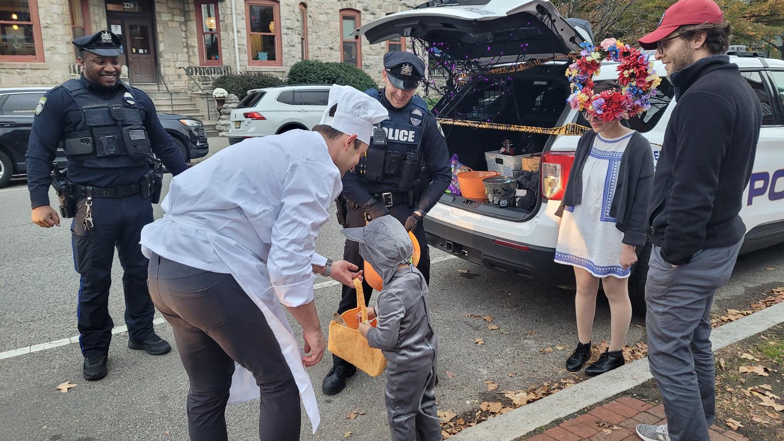 Public Safety officer watches as a child is trick or treating on the streets.