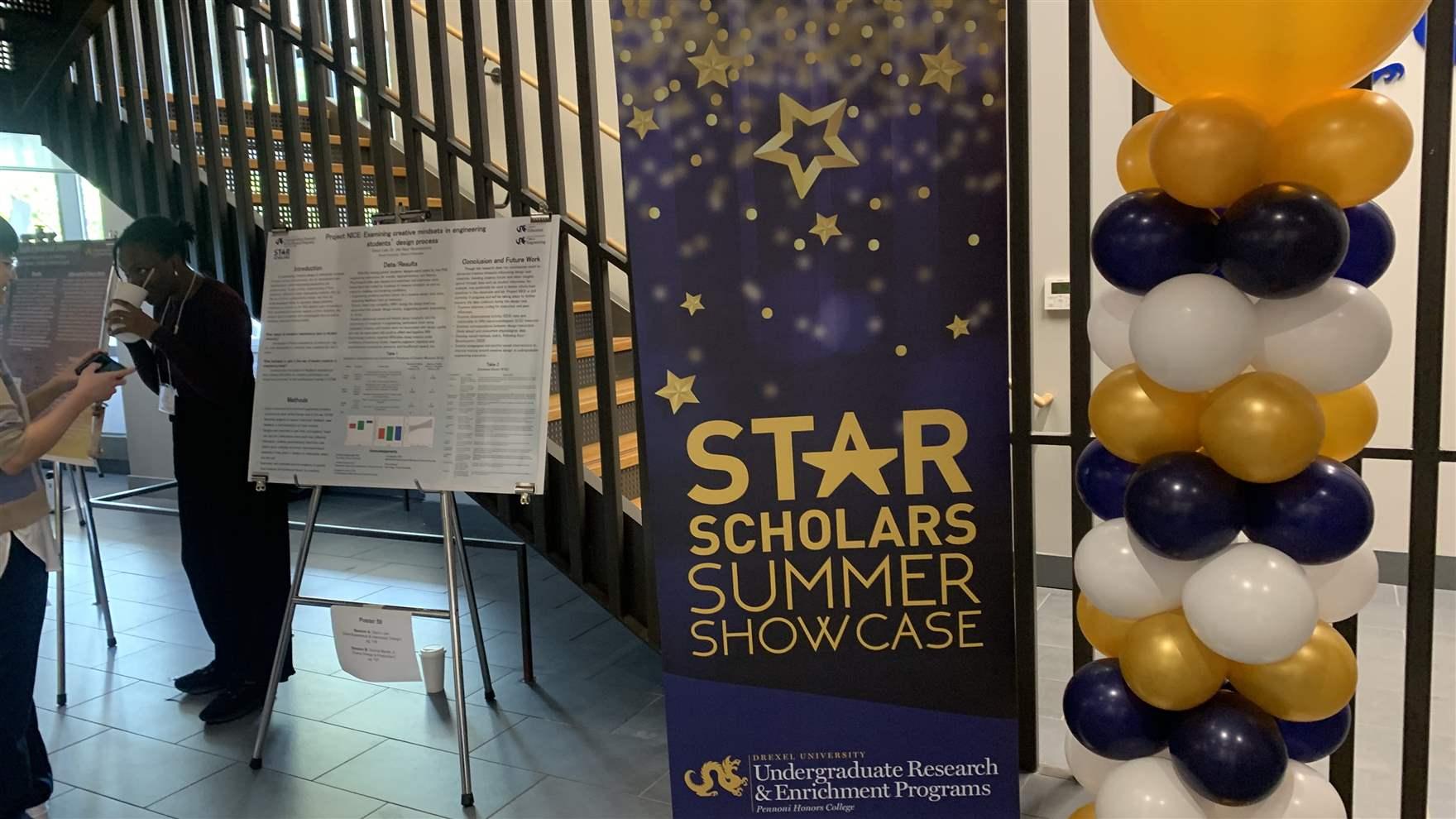 Blue and gold balloons and a sign reading STAR Scholar Summer Showcase in BEntley Hall