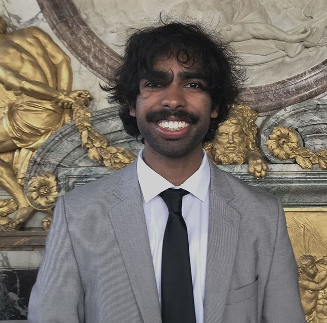 A headshot of a man in a grey suit and black tie