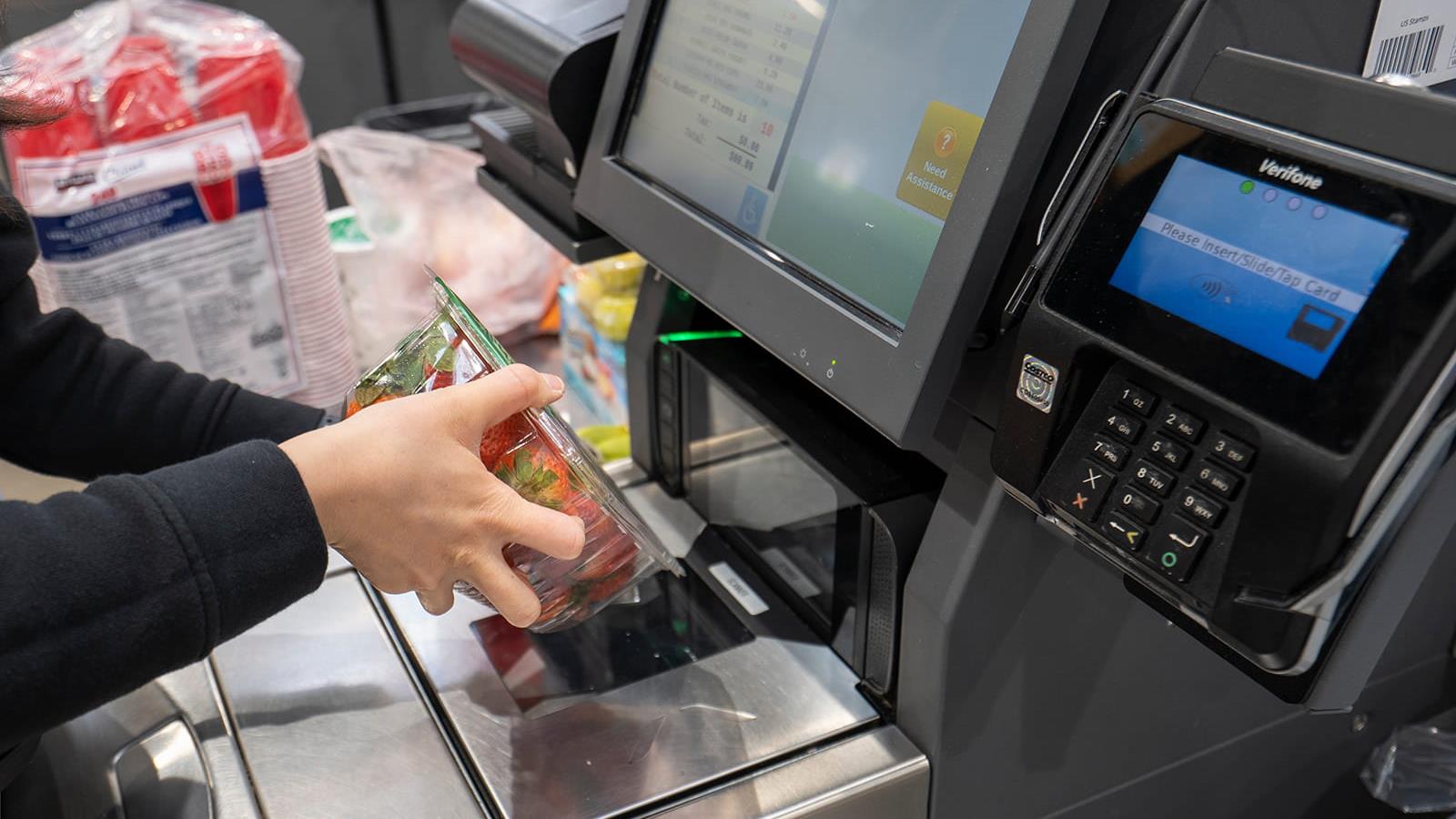 a person scans a carton of strawberries at a self-checkout in a grocery store