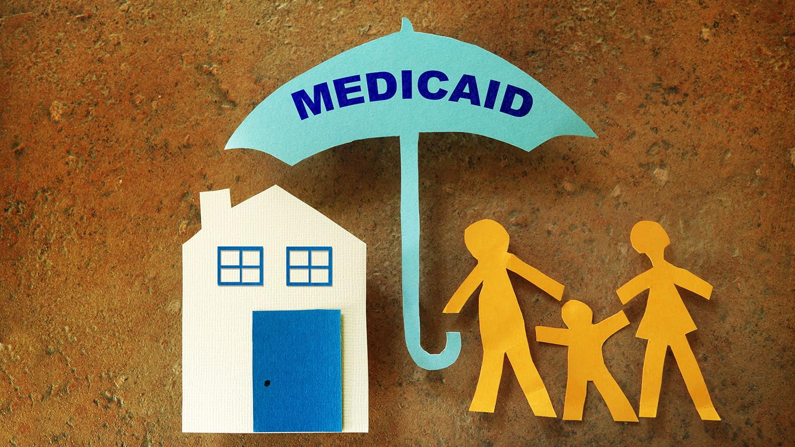 Paper cut outs of a home and family of three under a Medicaid umbrella