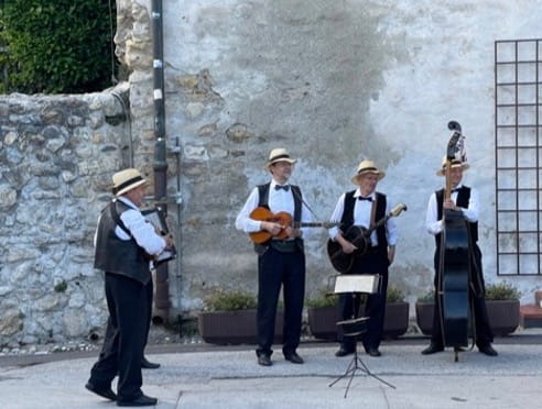 Four men in black and white clothing and hats playing music on a street.