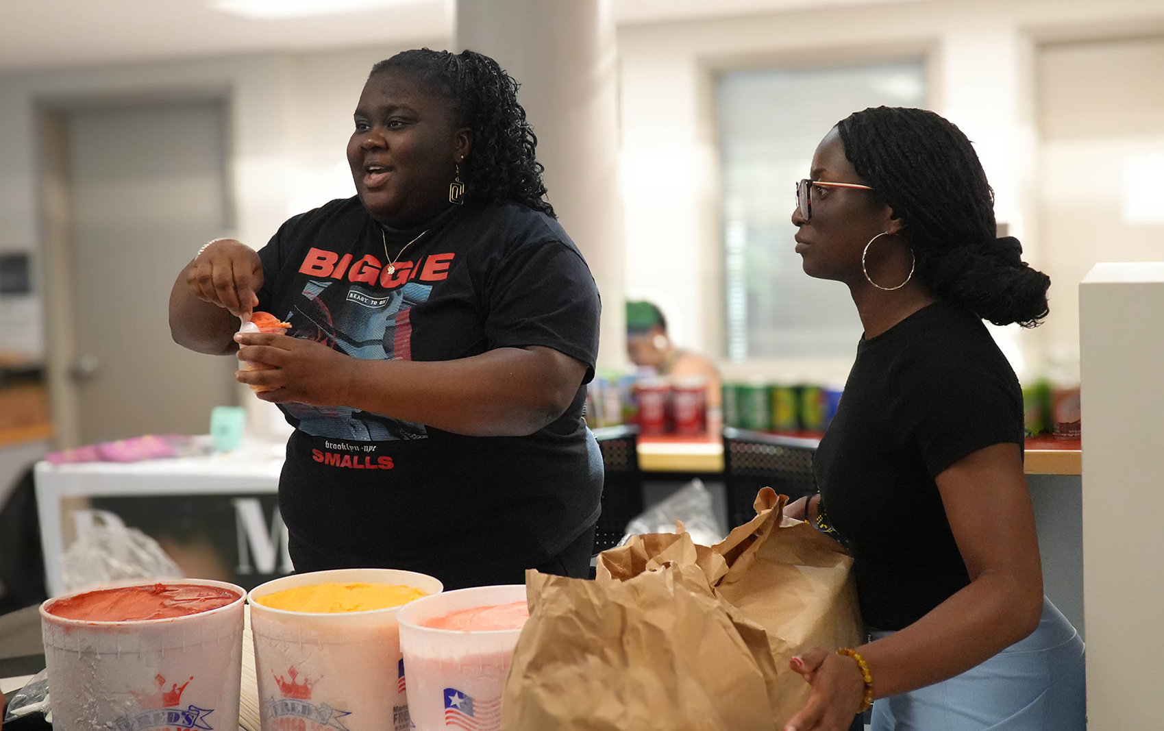 Two women scooping water ice.