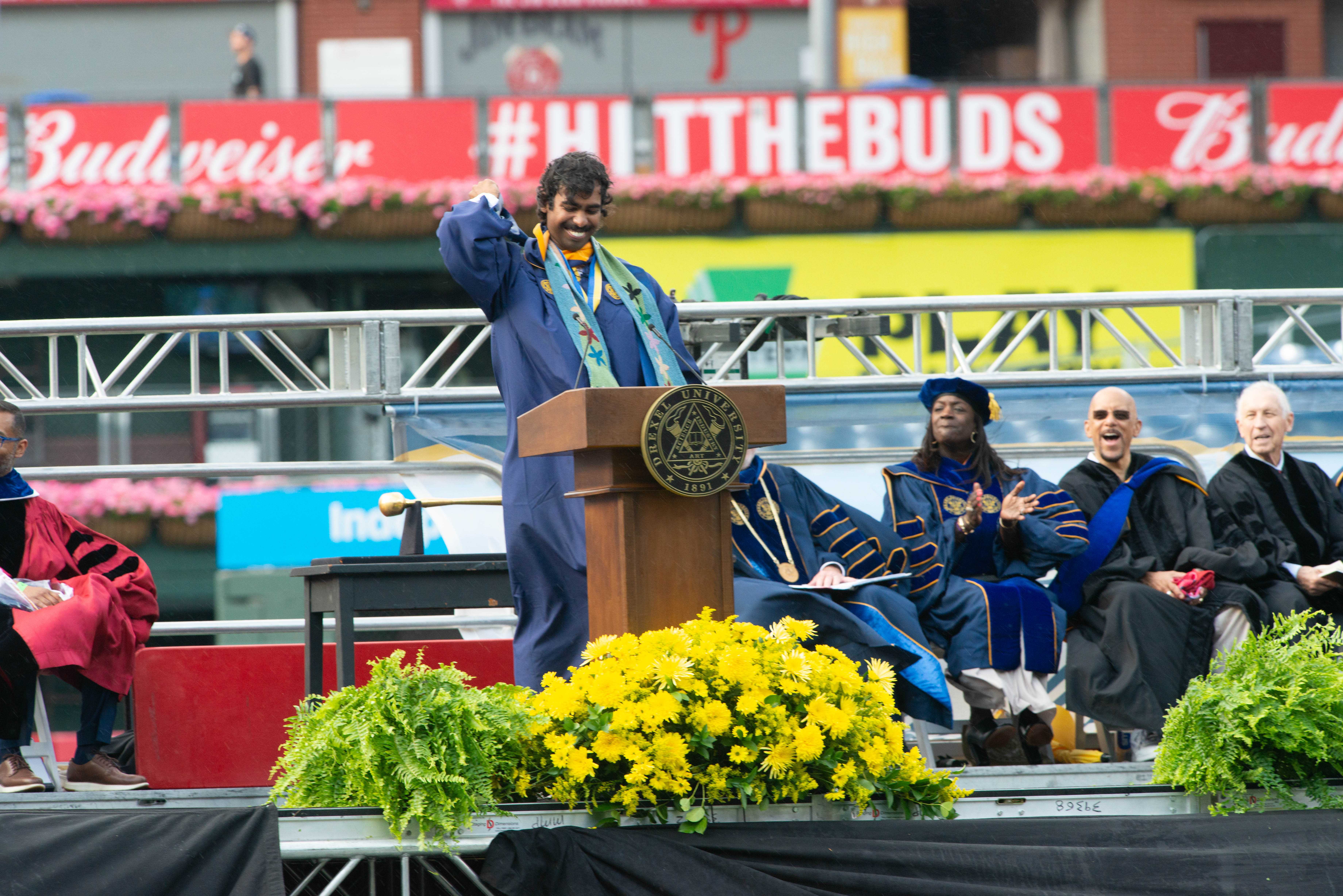 A wide view shot of Vivek Babu speaking at the podium at Drexel University's 2024 Commencement ceremony.