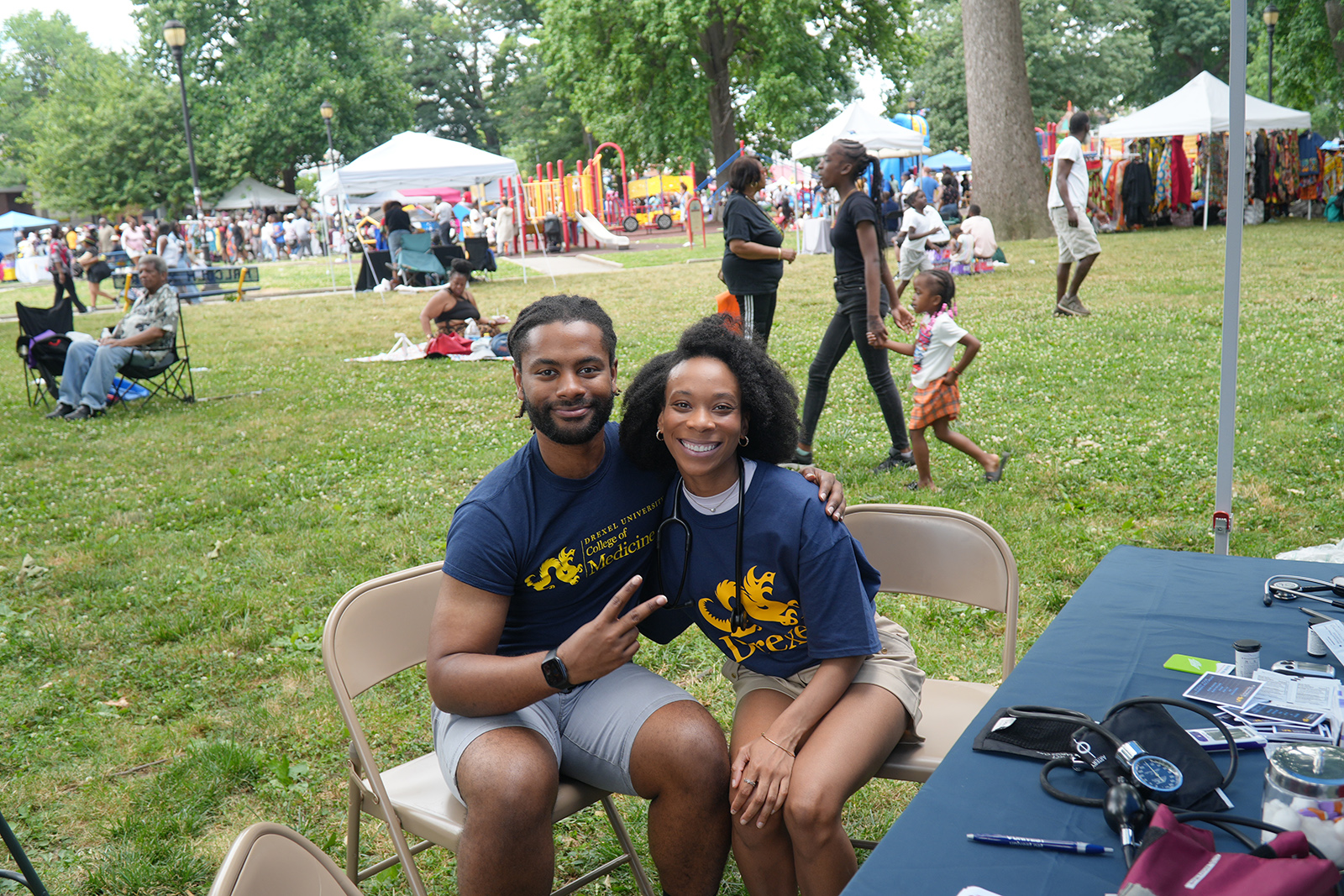 Students wearing Drexel COllege of Medicine shirts seated outside at a table.