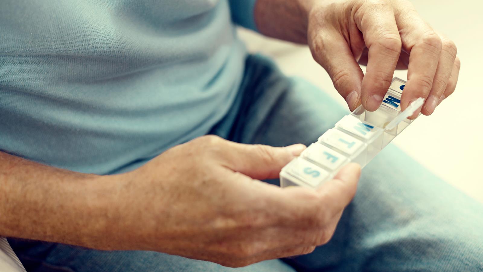 Older man holding daily pill organizer