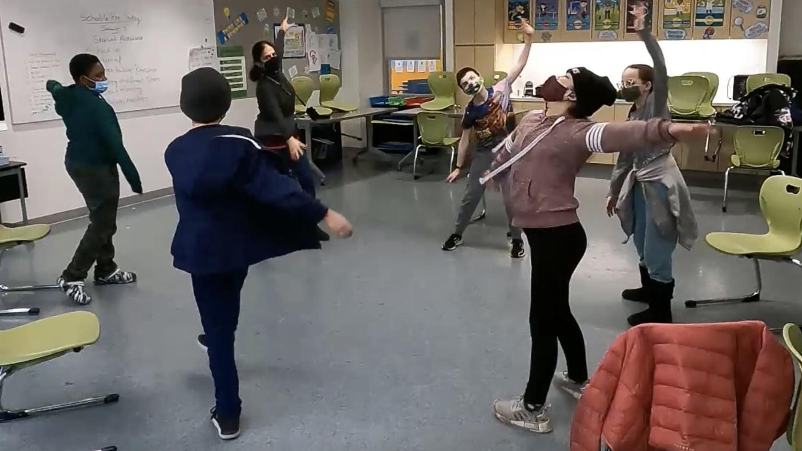 five students and one adult instructor standing in a large circle dancing